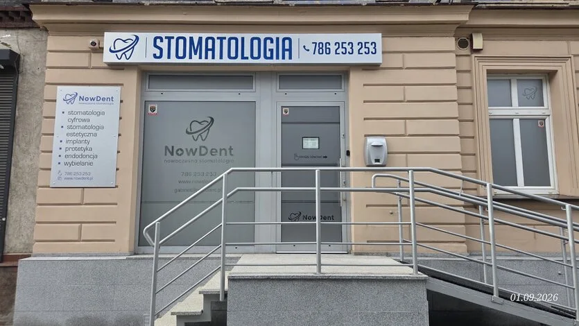Front budynku i wejście do nowoczesnego gabinetu dentystycznego NowDent z numerem kontaktowym i informacją o ofercie